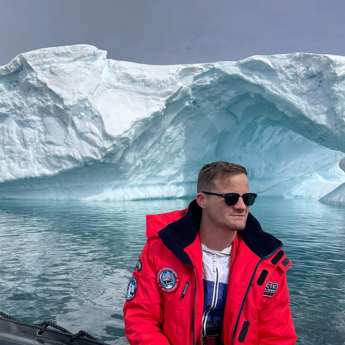 Nick in a red jacket in front of an iceberg in Antarctica